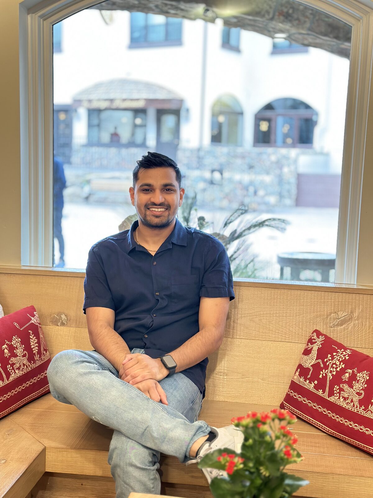 Vividh smiling, seated by a window at a cafe