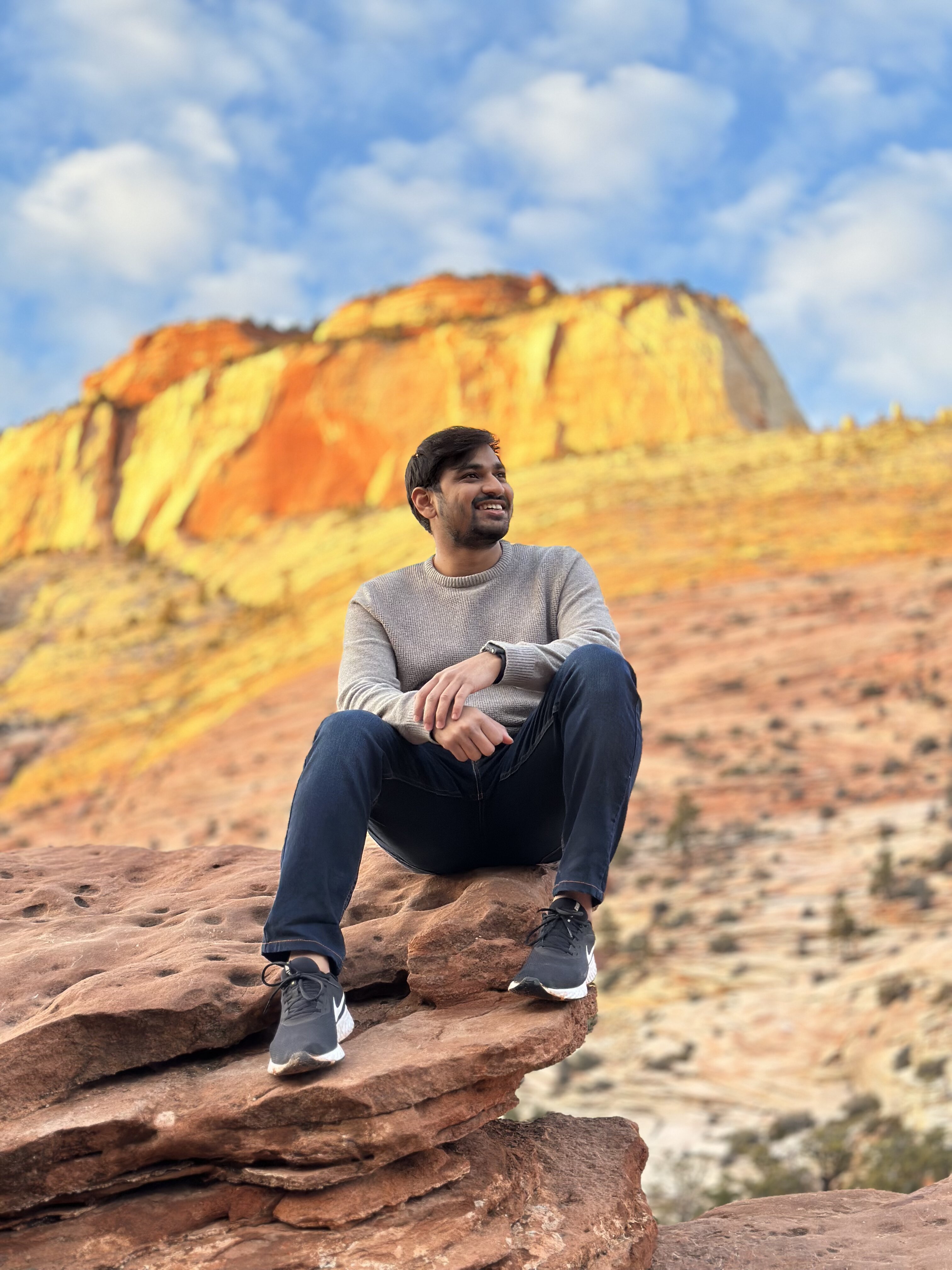 Vividh sitting on a red rock ledge in Zion